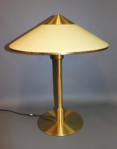 Bordlampe model kongelys i messing med  hvid akrylskærm med messingkant.
5000m2 udstilling. 
