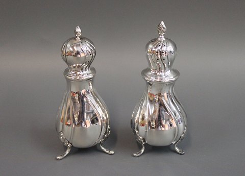 Three legged salt and pepper castors, hallmarked silver. In rococo style on fine 
feet and with fine Windings.
5000m2 showroom.
